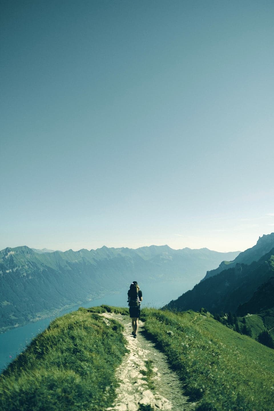 A hiker walking a narrow ridge trail above a valley
