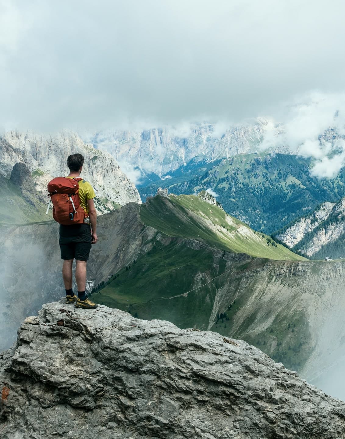 A hiker with a red backpack standing on a rocky summit